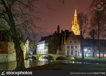 Night landscape at Lake Minnewater with church and bridge in Bruges, Belgium