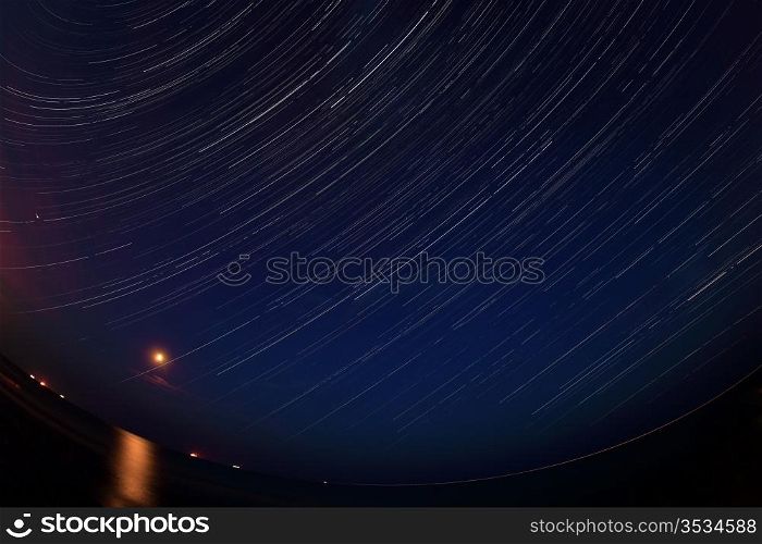 Night landscape, night sky with moving stars over the sea. Moon