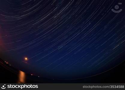 Night landscape, night sky with moving stars over the sea. Moon