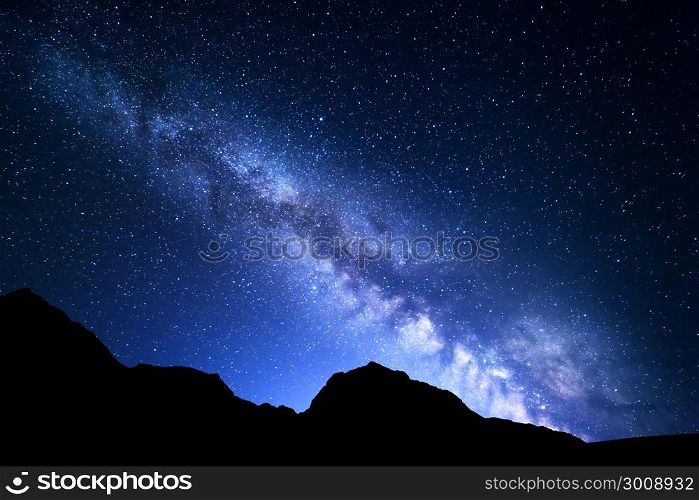 Night landscape with colorful Milky Way and blue light at mountains. Starry sky with rocks at summer. Beautiful Universe