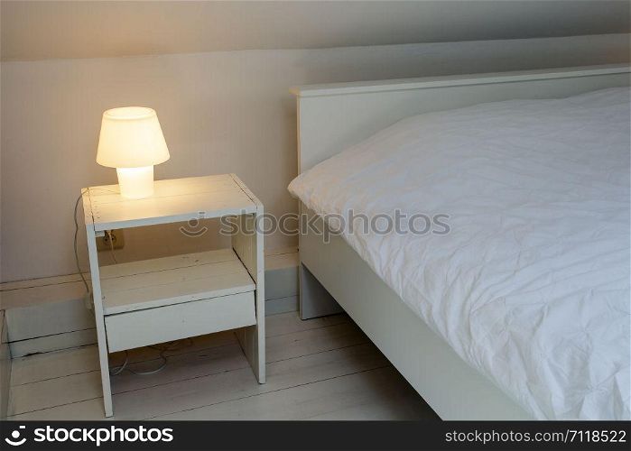 Night light lamp next to bed in the bedroom, white wooden floor and bed, modern design clean. Night light lamp next to bed in the bedroom, white wooden floor and bed, modern design