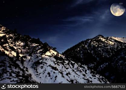 Night mountain winter landscape with yellow moon and stars