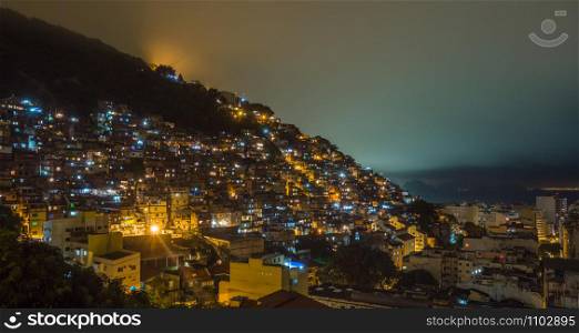 Night over Brazilian favelas on the hill with city downtown below, Rio De Janeiro, Brazil