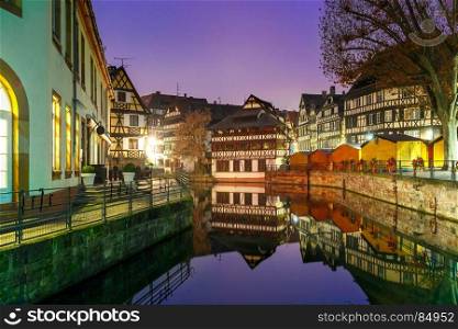 Night Petite France in Strasbourg, Alsace. Traditional Alsatian half-timbered houses with mirror reflections in Petite France during twilight blue hour, Strasbourg, Alsace, France