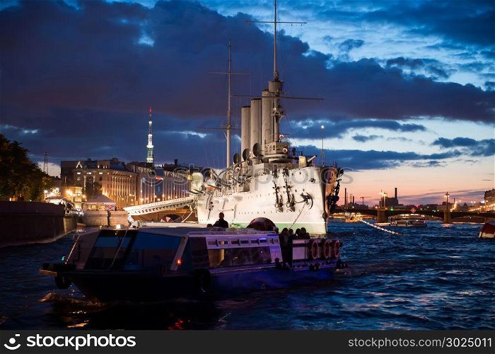 Night photo of the cruiser Aurora, view from the motor ship. Night shooting in the city of St. Petersburg.