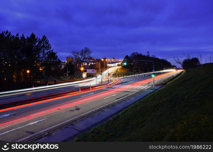 Night photo traffic on the road. Evening landscape with cars. Cars with lights and blurred color lines.