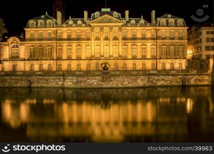 Night photography with the famous Rohan Palace from Strasbourg, France and its reflection in Ill river water.