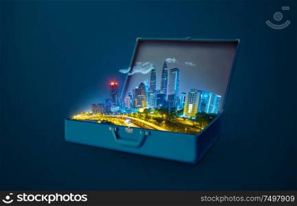 Night scene modern city skyscraper in an open retro vintage suitcase isolated on blue background .
