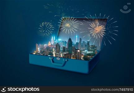 Night scene modern city skyscraper with fireworks in an open retro vintage suitcase isolated on blue background .