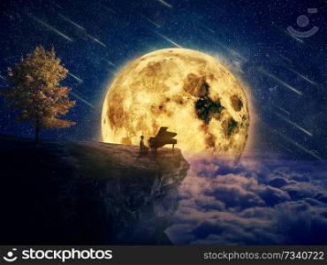 Night scene with a boy, musician standing at the edge of a cliff chasm with his piano. Waiting for music inspiration in the center of nature, over a full moon night background.