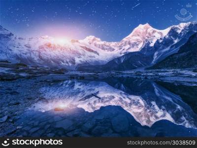 Night scene with himalayan mountains and mountain lake at starry night in Nepal. Landscape with high rocks with snowy peak and sky with stars and moon reflected in water. Moonrise Beautiful Manaslu. Himalayn mountains and mountain lake at starry night in Nepal
