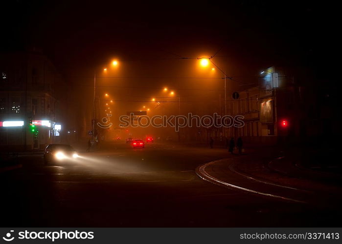 Night scene with moving carsand walking people in the fog