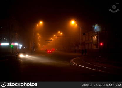 Night scene with moving carsand walking people in the fog