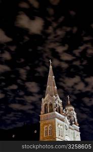 Night shot of a Catholic church with eerie sky.