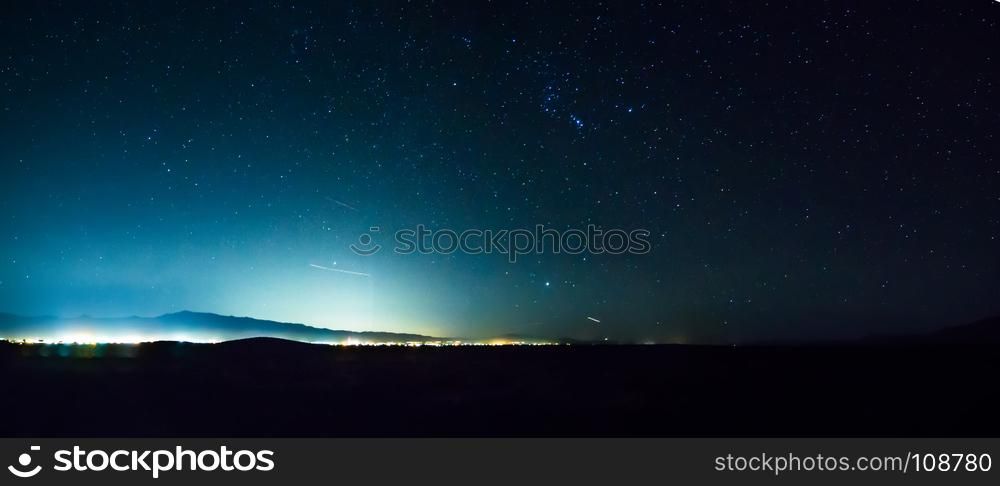 night sky in death valley with pahrump city lights in distance