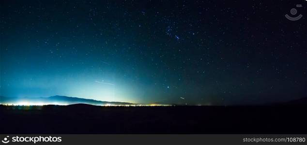 night sky in death valley with pahrump city lights in distance
