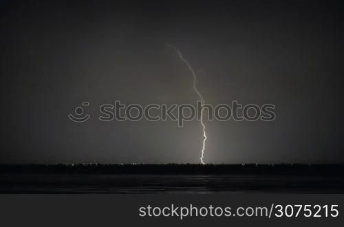 Night thunderstorm on the coast. Lightning strikes in distant city