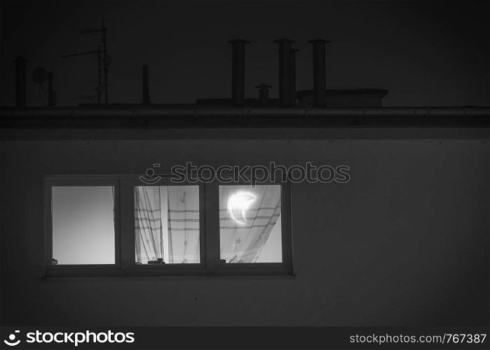 Night time. Rural house, window in the room with lamp in form of moon. Window in the room with moon lamp