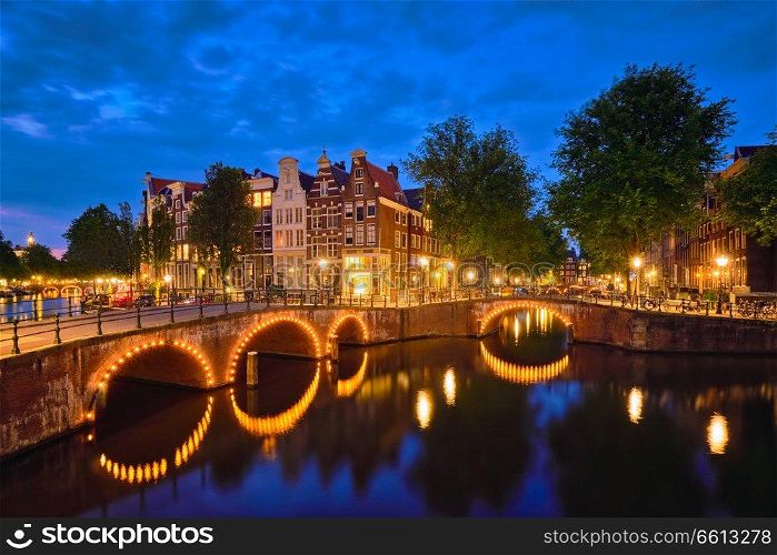 Night view of Amterdam cityscape with canal, bridge and medieval houses in the evening twilight illuminated. Amsterdam,  Netherlands. Amterdam canal, bridge and medieval houses in the evening