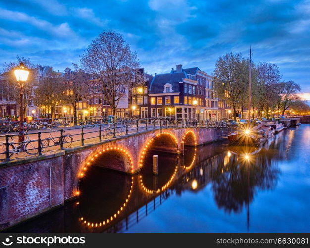 Night view of Amterdam cityscape with canal, bridge and medieval houses in the evening twilight illuminated. Amsterdam,  Netherlands. Amterdam canal, bridge and medieval houses in the evening