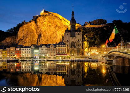 Night view of Dinant town, Collegiate Church of Notre Dame de Dinant over River Meuse and Pont Charles de Gaulle bridge and Dinant Citadel illuminated in the evening. Dinant, Belgium. Night view of Dinant town, Belgium