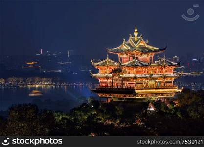 Night view of illuminated Cheng Huang Ge (City God Pavillion) with West Lake and city skyline on background, Hangzhou, China. Night view of illuminated Cheng Huang Ge, also known as City God Pavillion, Hangzhou, China