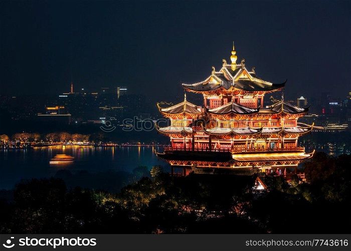 Night view of illuminated Cheng Huang Ge  City God Pavillion  with West Lake and city skyline on background, Hangzhou, China. Night view of illuminated Cheng Huang Ge, also known as City God Pavillion, Hangzhou, China