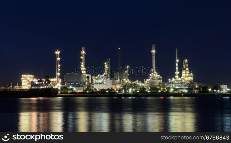 Night view of oil refinery plant illuminated at night with reflection on the river