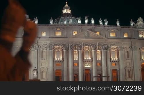 Night view of St. Peters Basilica in Vatican City. Female tourist using tablet PC to take some photos of famous Catholic church, bright example of Renaissance architecture