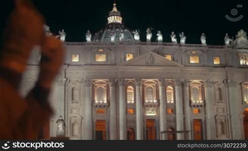 Night view of St. Peters Basilica in Vatican City. Female tourist using tablet PC to take some photos of famous Catholic church, bright example of Renaissance architecture