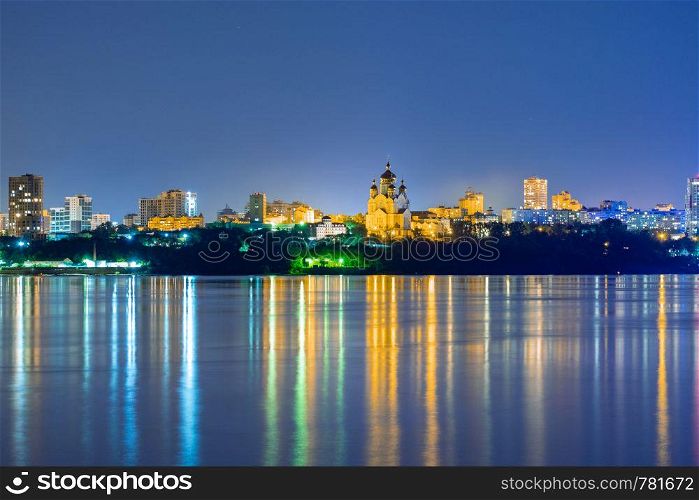 Night View of the city of Khabarovsk from the Amur river. Blue night sky. The night city is brightly lit with lanterns. Night View of the city of Khabarovsk from the Amur river. Blue night sky. The night city is brightly lit with lanterns.