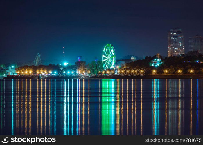 Night View of the city of Khabarovsk from the Amur river. Blue night sky. The night city is brightly lit with lanterns. Night View of the city of Khabarovsk from the Amur river. Blue night sky. The night city is brightly lit with lanterns.