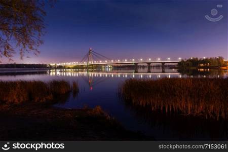 Night view of the Pivnichnyi Bridge (ex Moskovsky bridge) on the Dnieper river in Kiev, Ukraine, at evening during the blue hour
