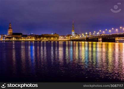 Night view to the historical city center and Stone bridge from the banks of Daugava river colored with street lights, Riga, Latvia