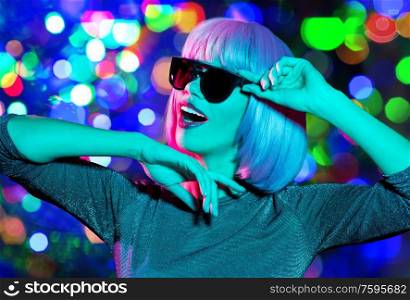 nightlife, fashion and people concept - happy young woman wearing pink wig and black sunglasses dancing over night lights background. happy woman in pink wig and sunglasses dancing