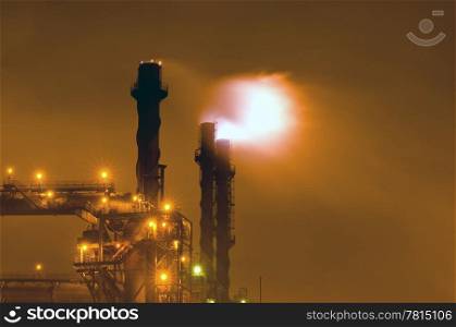 Nightly scene of an industrial plant with huge flaring stacks