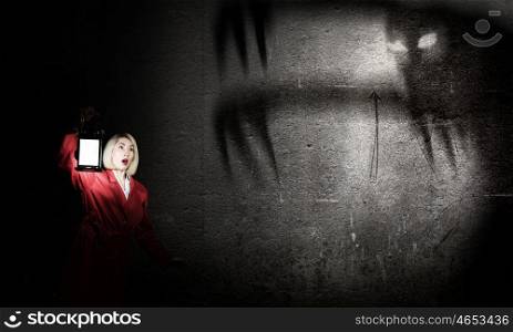 Nightmare. Young blond woman in red cloak with lantern