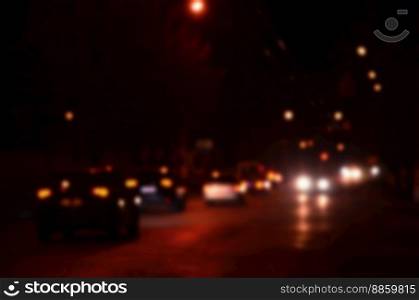 Nights lights of the big city, the blurred night avenue with bokeh traffic lights and headlights of the approaching cars. Blurred landscape of night city
