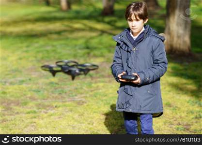 Nine-year-old girl operating toy drone flying or hovering by remote control in a park.. Nine-year-old girl operating toy drone flying by remote control