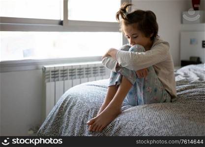 Nine-year-old girl sitting in bed at home bored by confinement. Nine-year-old girl sitting in bed bored by confinement