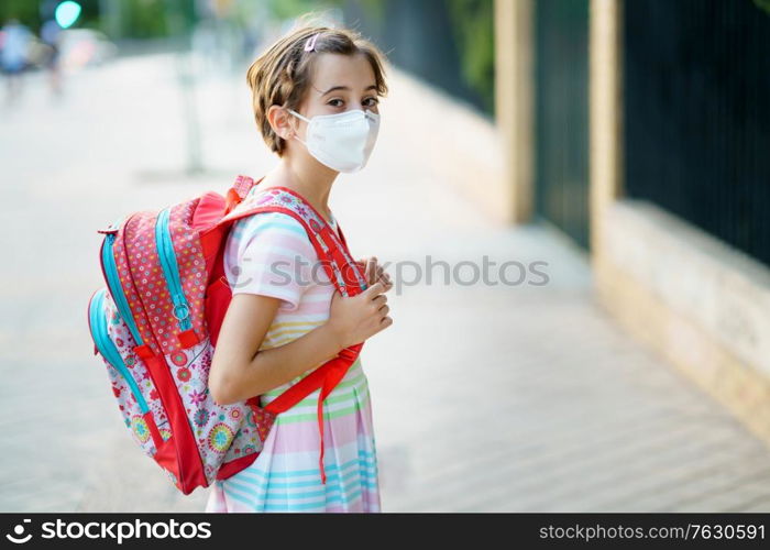 Nine years old girl goes back to school wearing a mask and a schoolbag outdoors.. Nine years old girl goes back to school wearing a mask and a schoolbag.