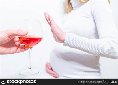 No alcohol during pregnancy. Young pregnant woman refuses to drink wine, making stop gesture to glass, free space
