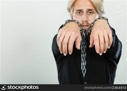 No freedom, social problems concept. Sad man with chained hands, studio shot on light grey background. Sad man with chained hands, no freedom