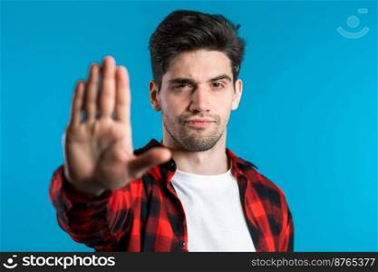 No, never, handsome brunette man disliking and rejecting gesture by stop sign. Portrait of young successful confident guy isolated on blue background.. No, never, handsome brunette man disliking and rejecting gesture by stop sign. 