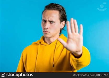 No, never, handsome brunette man disliking and rejecting gesture by stop sign. Portrait of young successful confident guy isolated on blue background. High quality photo. No, never, handsome brunette man disliking and rejecting gesture by stop sign. Portrait of young successful confident guy isolated on blue background