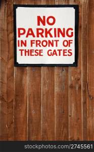 no parking in front of these gates vintage sign at a wooden fence background