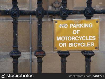 no parking of motorcycles or bicycles golden sign hanging on a metallic fence