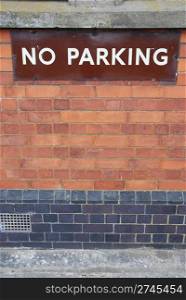 no parking sign on a red brick wall