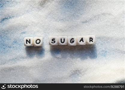 no sugar text blocks with white sugar on wooden background, suggesting dieting and eat less sugar for health concept