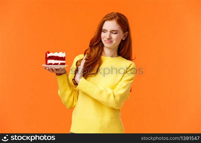 No thanks, dont want. Cute redhead girl trying resist temptation take bite delicious sweets, holding tasty cake and showing stop, refusal or rejection with grimacing face, express aversion, dislike.. No thanks, dont want. Cute redhead girl trying resist temptation take bite delicious sweets, holding tasty cake and showing stop, refusal or rejection with grimacing face, express aversion, dislike